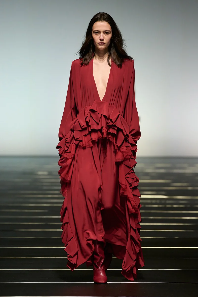 Модель Alberta Ferretti в длинном винно-красном платье с глубоким вырезом и воланами