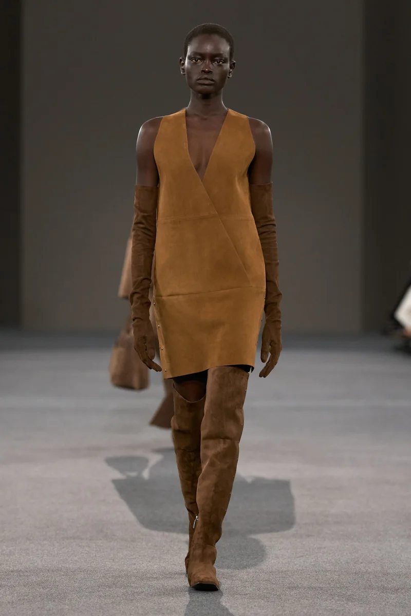 Модель Max Mara в коньячном замшевом сарафане и высоких сапогах в тон